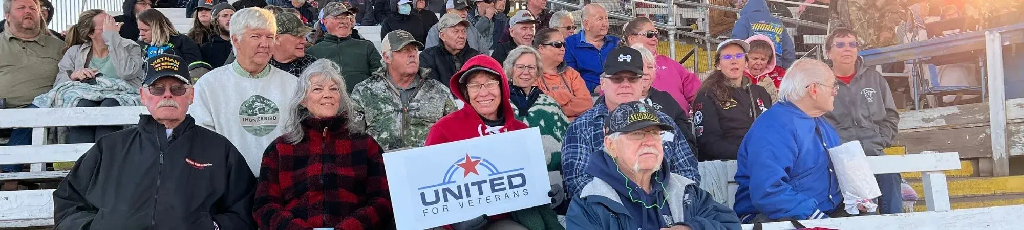 Veterans and their loved ones smile in the Hibbing Raceway stands at a United for Veterans Connections activity